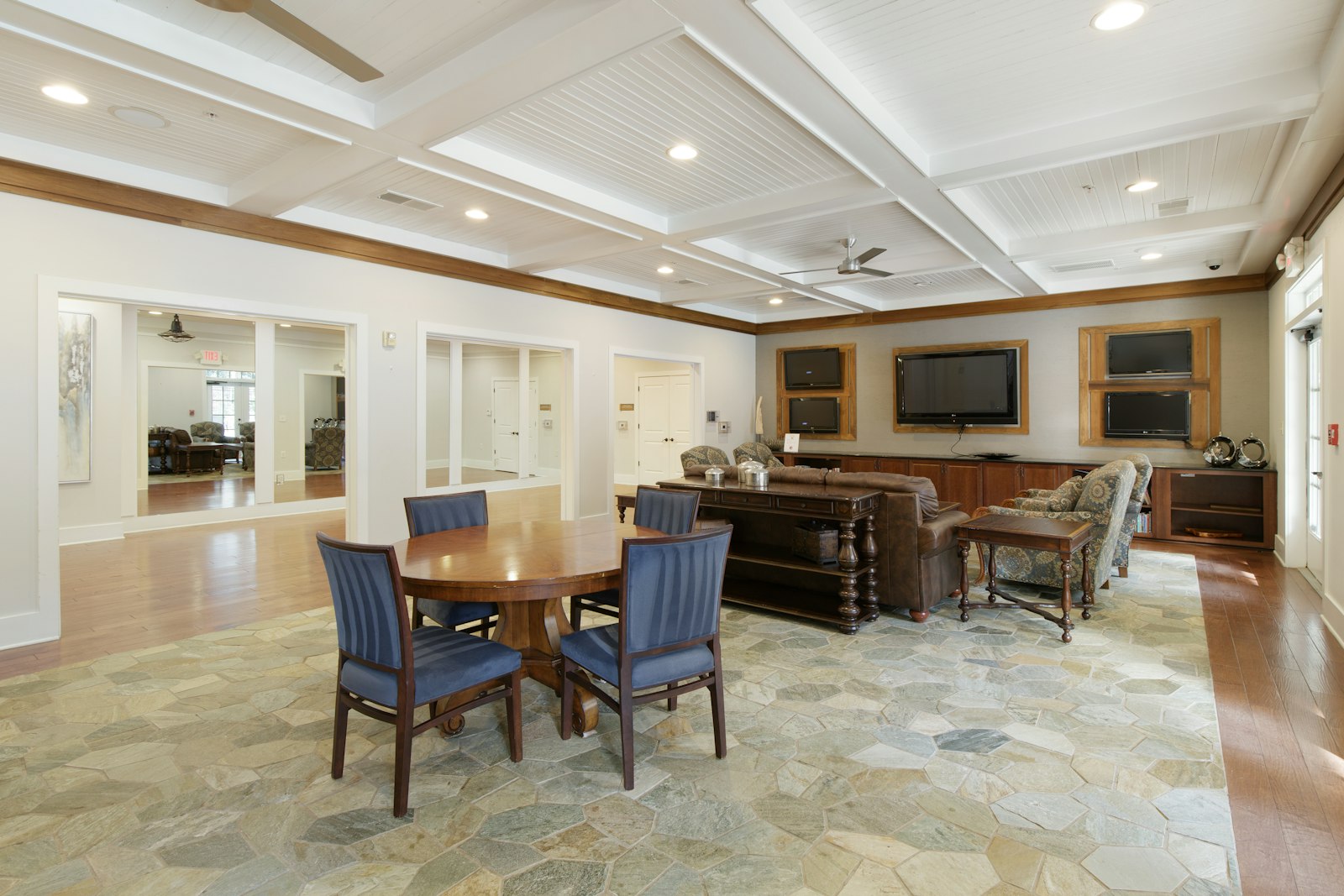 An assisted living common room with wall-mounted TVs